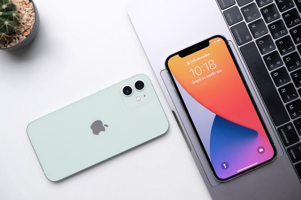 Imagem com 2 modelos de iPhone 12, um cinza virado com a tela para baixo e outro com a tela ligada para cima