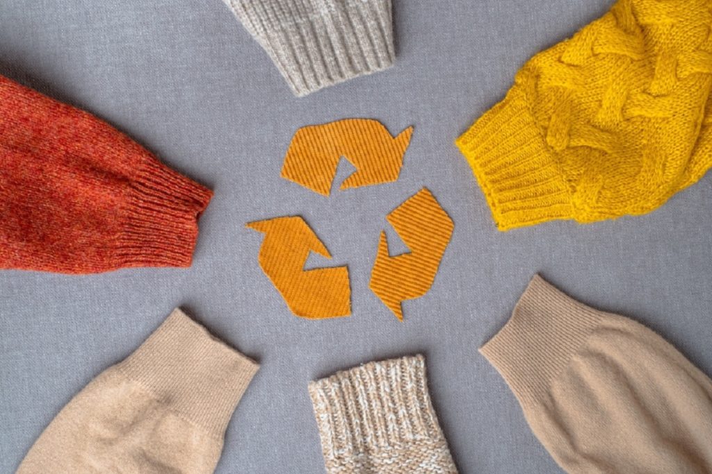 Reciclagem de roupas. Roupas usadas. Moda ecológica e sustentável. mangas de suéteres de lã colorida em cores quentes.