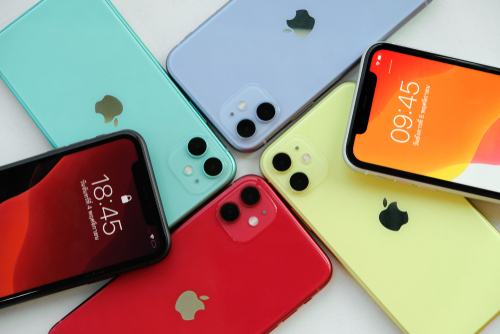 Modelos coloridos de iphone 11 dispostos, juntos, sobre uma bancada/mesa. 