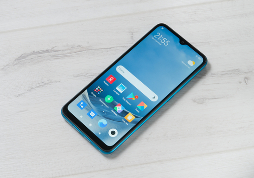 Foto do smartphone Xiami Redmi 9A. O aparelho está sobre a mesa, com a tela ligada e virada para cima.