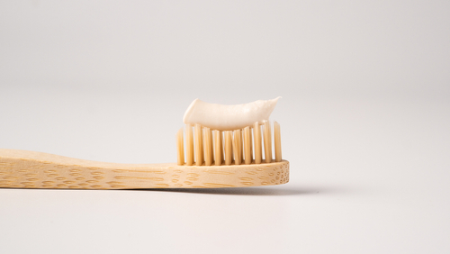 Escova de dente de bambu com pasta de dente nas cerdas.