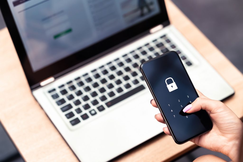 Smartphone com laptop ao fundo. Bloqueio de senha do telefone para segurança cibernética móvel ou senha de verificação de login no aplicativo.