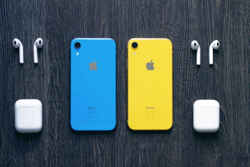 Dois iphones XR sobre uma mesa. O do lado esquerdo da foto é azul, e o do lado direito é amarelo. 