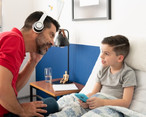 Pai com um fone de ouvido conversando com seu filho. 
