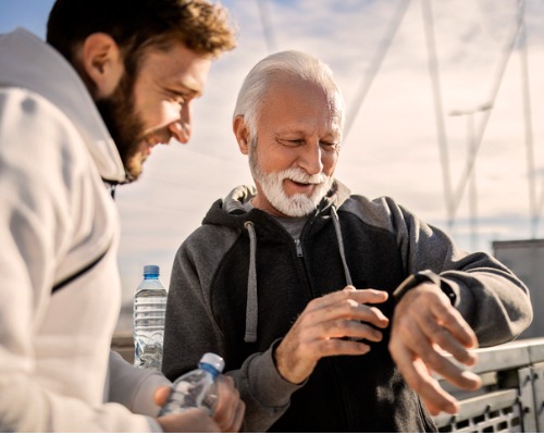 Senhor com um smartwatch mostrando o relógio para um homem mais novo. 