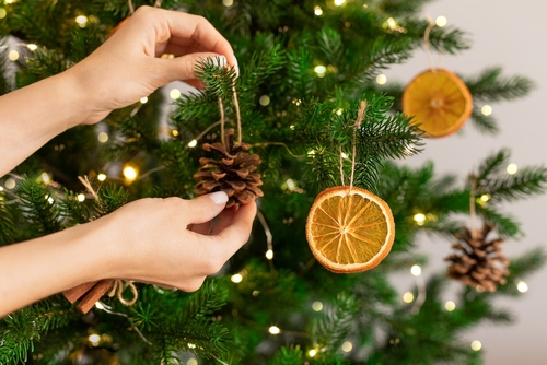 Mãos femininas pendurando decoração artesanal na árvore de Natal. Natal sustentável, desperdício zero, amigo do ambiente.