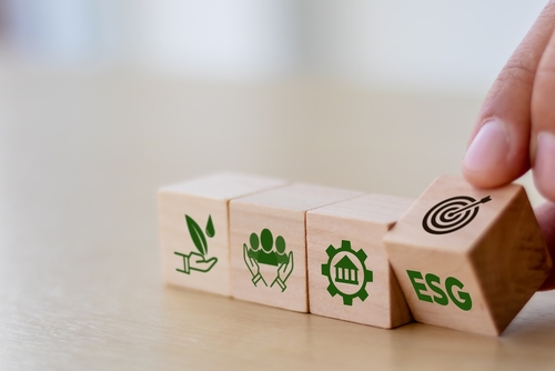 Conceito ESG de ambiental, social e governança. Desenvolvimento Corporativo Sustentável. Mão vira cubos de madeira com configuração de destino para ícone ESG com outros ícones ESG em letras brilhantes.