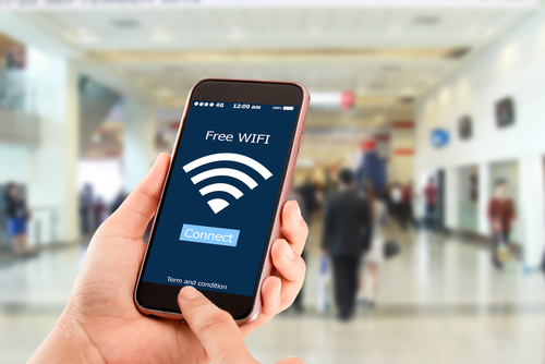 Conceito wi-fi gratuito.Mãos segurando telefone celular no homem em uma espécie de shopping center.