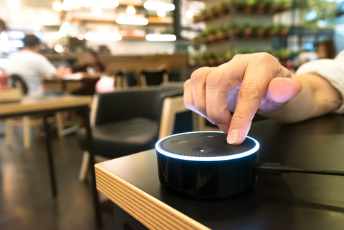 Ponto de dedo para Amazon Echo dot versão 2, o dispositivo de streaming de reconhecimento de voz da Amazon em cafeteria.