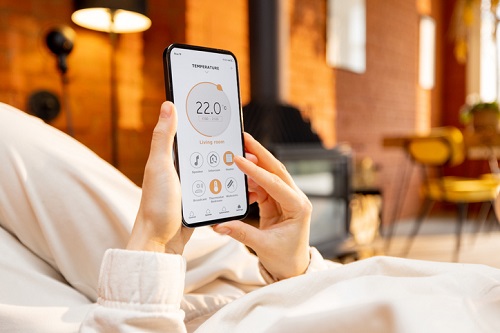 Mulher segurando o telefone com aplicativo doméstico inteligente em execução para controle de temperatura de aquecimento, enquanto está relaxado em casa. Close na tela do dispositivo