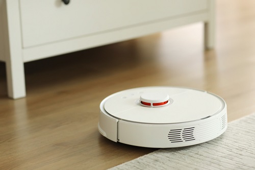aspirador de pó de robô branco limpa o chão de detritos, limpeza doméstica com um aspirador de pó elétrico, tecnologia de limpeza de robô elétrico de aspirador de pó, vista superior de um aspirador de pó de robô