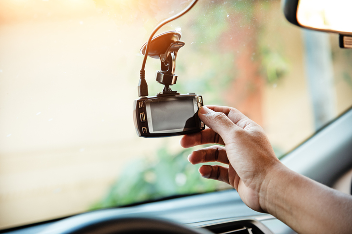 A mão humana está tocando a câmera CCTV do carro, para verificar o sistema antes do uso, a tecnologia para o usuário do carro, para uma direção segura e protegida, tom de luz quente, luz embaçada ao redor