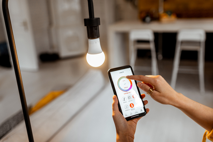Controlando a temperatura e a intensidade da lâmpada com um aplicativo para smartphone. Conceito de casa inteligente e gerenciamento de luz com dispositivos móveis