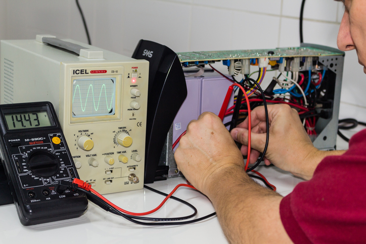 manutenção de uma UPS (Uninterruptible Power Supply) em uma bancada por um técnico.