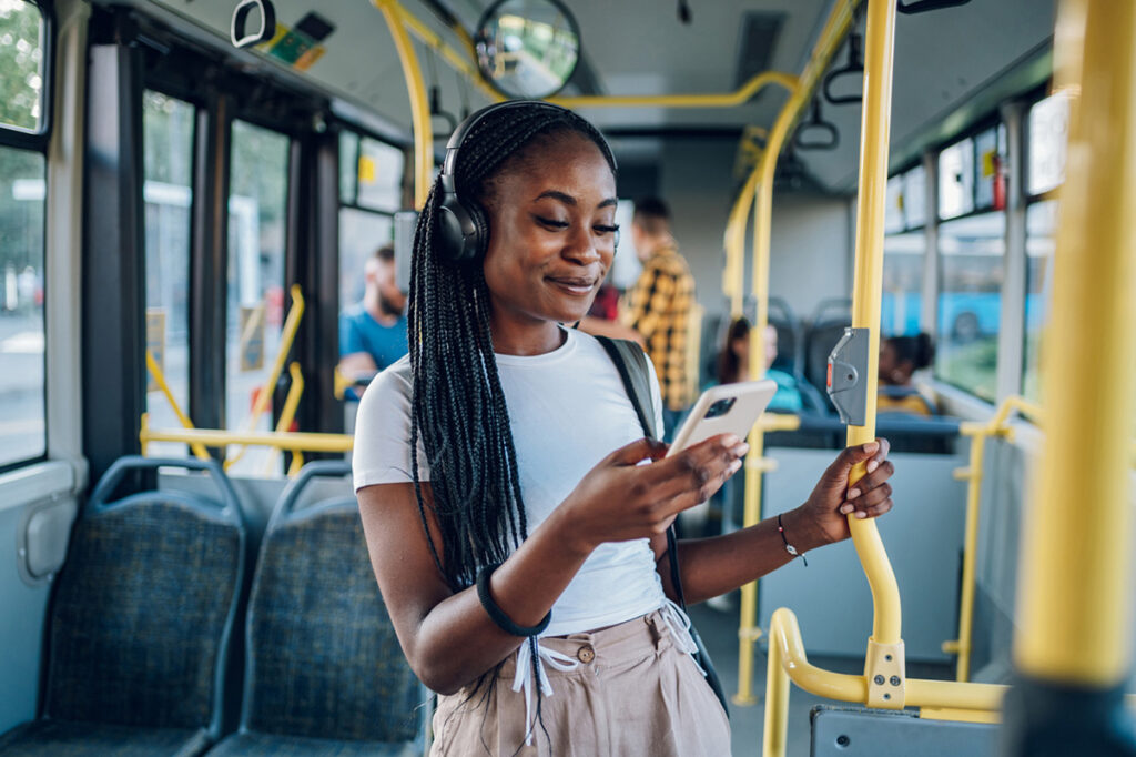Imagem mostrando uma mulher ouvindo música em um ônibus, representando qual é o melhor aplicativo de ouvir música.